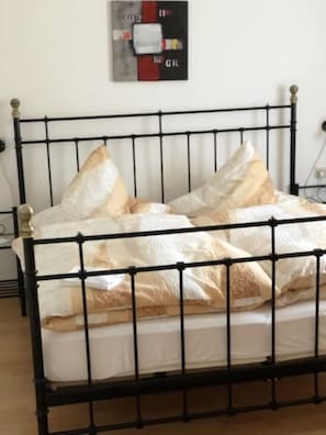 A bed with a metal frame, white bedding, and two pillows. - Herbstlaub Vacation Rental, stunning view of the countryside (Minheim)