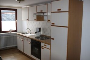 A kitchen with white cabinets, a window, a radiator, and a dishwasher. - Herbstlaub Vacation Rental, stunning view of the countryside (Minheim)