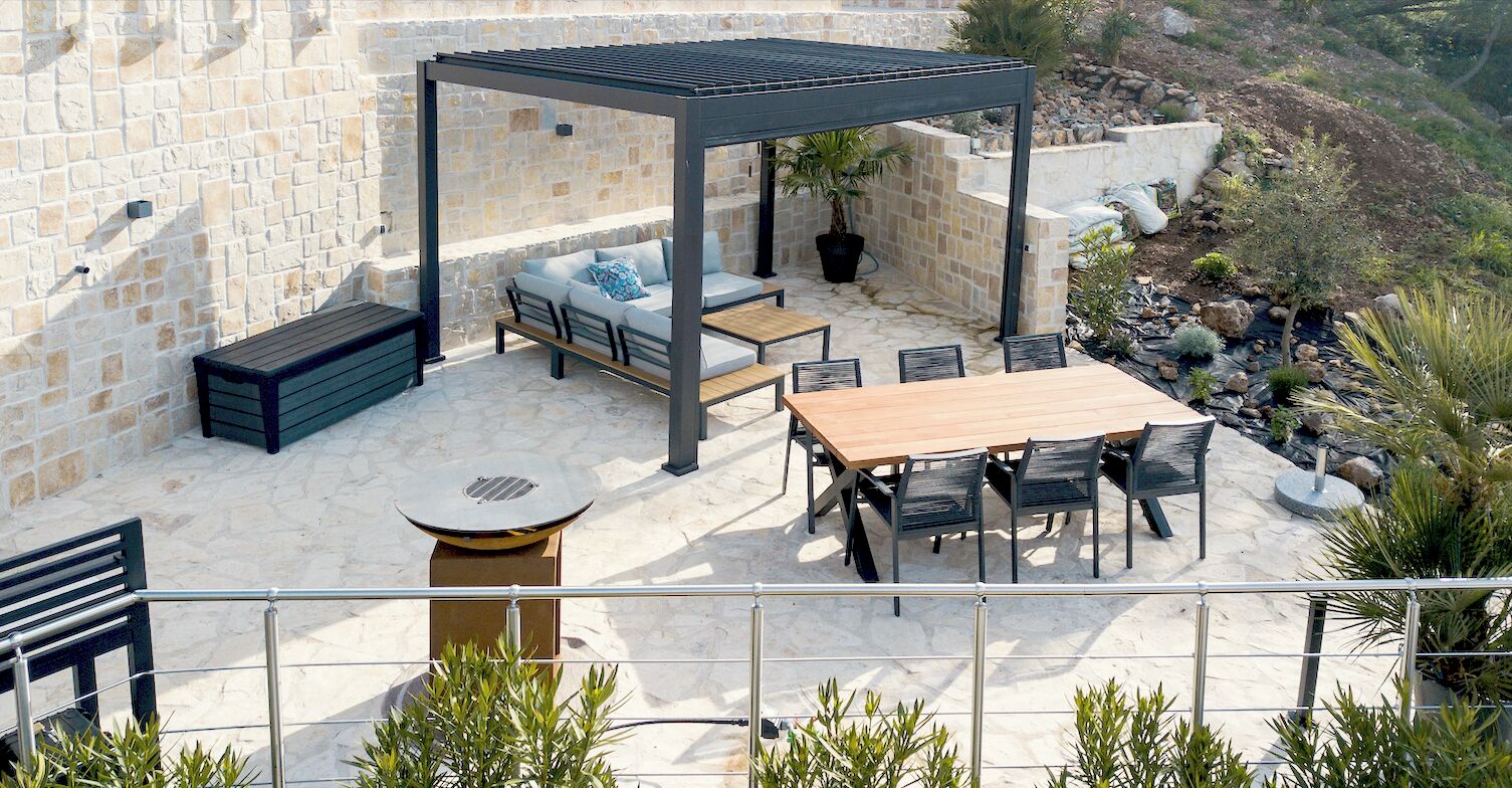 An outdoor patio with a pergola, seating, and a dining table.