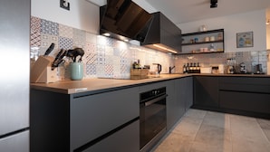 Una cocina moderna con horno integrado, cafetera y diversos utensilios de cocina sobre la encimera.