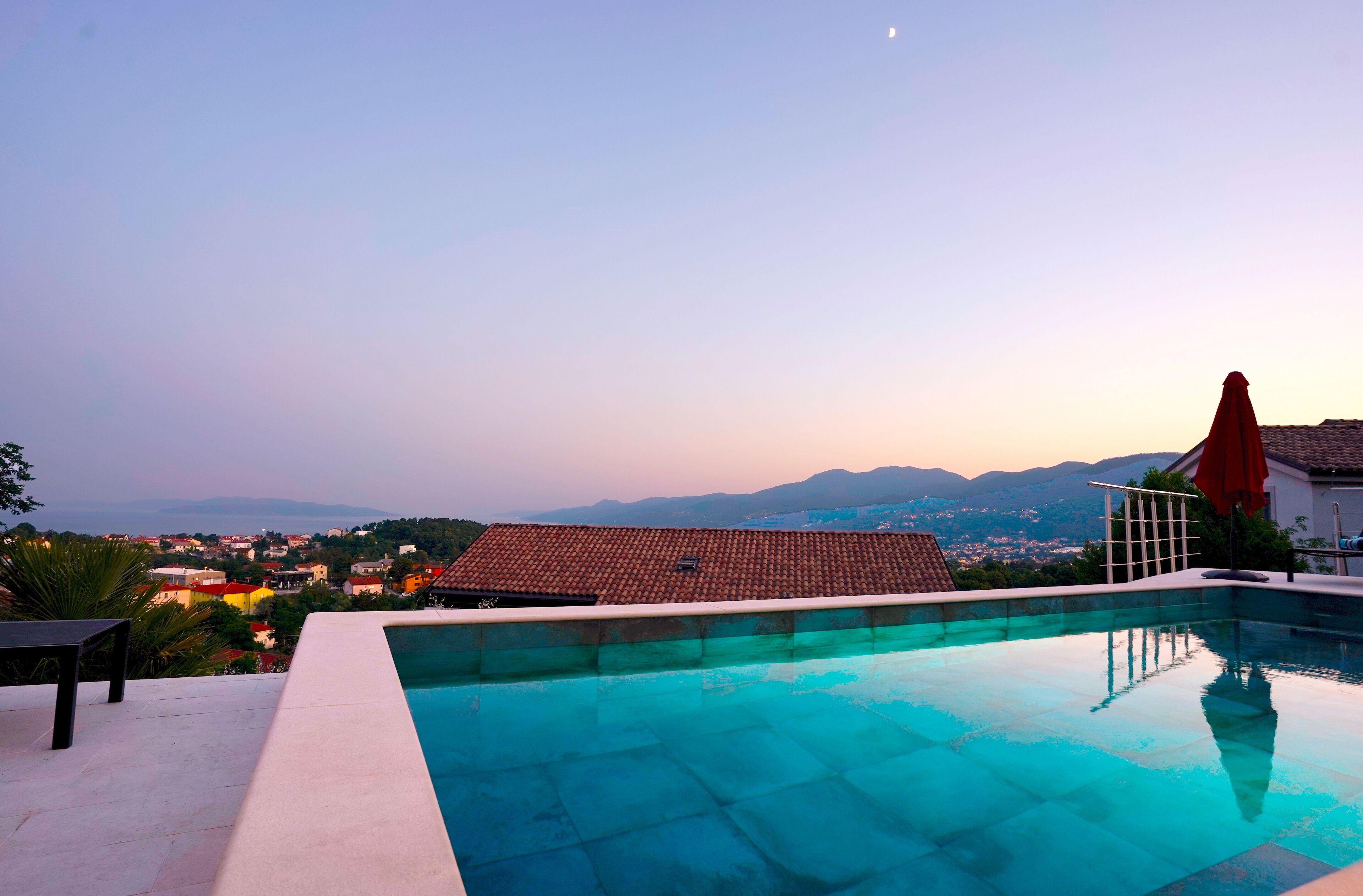 A swimming pool with a view of a town and mountains in the background.