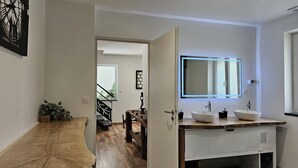 Een moderne badkamer met een grote spiegel, twee wastafels en een houten wastafelmeubel.