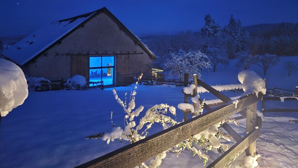 Een besneeerd landschap met een houten hut en een houten omheining.