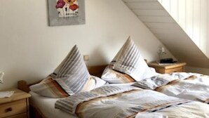 A bedroom with a sloped ceiling, a wooden bed frame, and a nightstand with a lamp. - Apartment "Moselblick", A great view of the greenery and enjoy the evening sun (Minheim)
