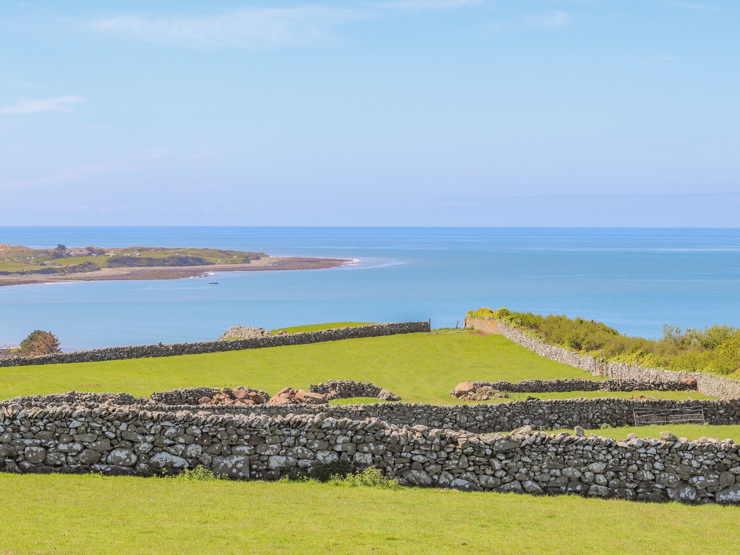 A coastal landscape with stone walls and grassy fields.