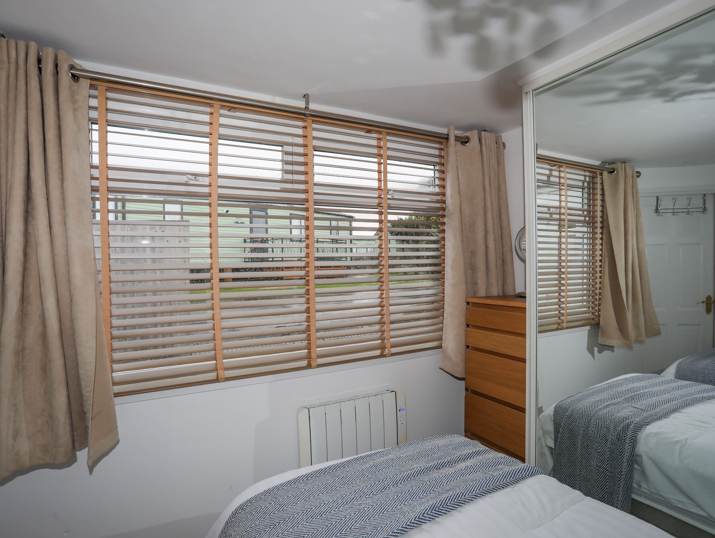 A bedroom with a bed, a dresser, and a radiator.