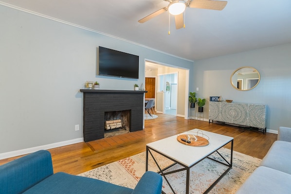 Una sala moderna con chimenea, televisor de pantalla plana y ventilador de techo.