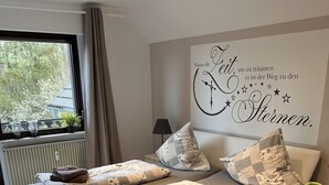 Un dormitorio moderno con cama, una mesita, una lámpara y un adorno en la pared.