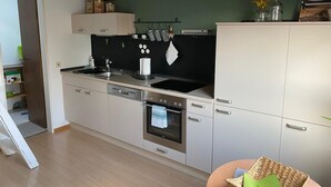 Una cocina moderna con salpicadero negro, electrodomésticos de acero inoxidable y techo de madera.