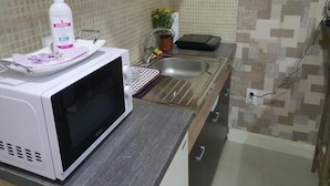 A kitchen with a white microwave, a sink, and a potted plant.