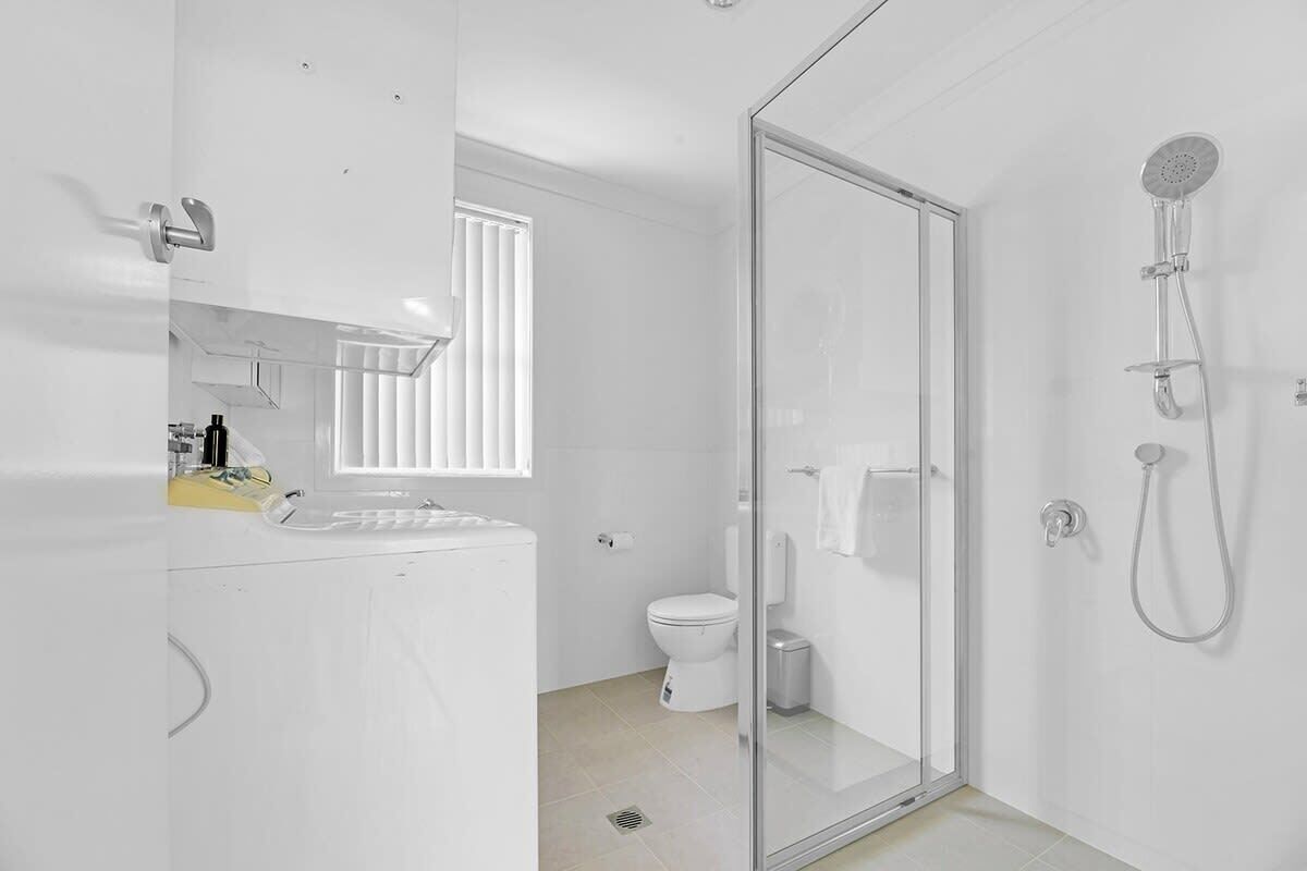 Ein modernes Badezimmer mit Duschkabine, Toilette und Waschbecken mit Spiegel.
