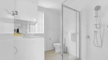 Ein modernes Badezimmer mit Duschkabine, Toilette und Waschbecken mit Spiegel.
