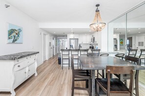 A modern kitchen with a dining area, wooden flooring, and a chandelier. - Renovated 2B Gulf Front Condo @ Emerald Isle 805! (Pensacola Beach)