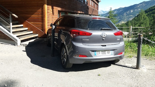 A grey Hyundai car parked in front of a wooden building with a staircase leading to a covered porch.