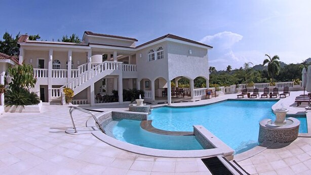A large, two-story building with a swimming pool, outdoor seating, and a staircase leading to a balcony. - Luxury Villas - Mandatory All-Inclusive (Puerto Plata)