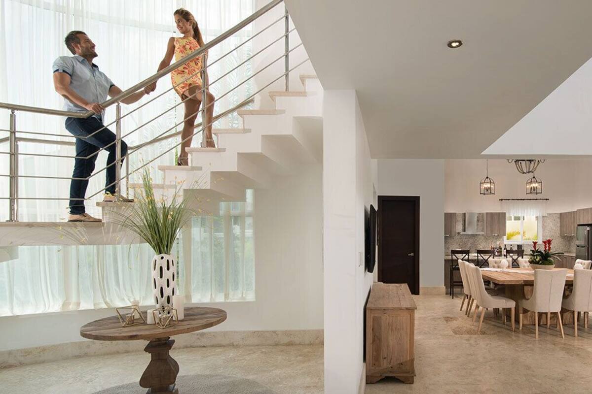 A modern living space with a staircase, dining area, and kitchen.