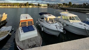 Un port de plaisance où sont amarrés plusieurs bateaux, l’eau est calme et le ciel est partiellement nuageux.