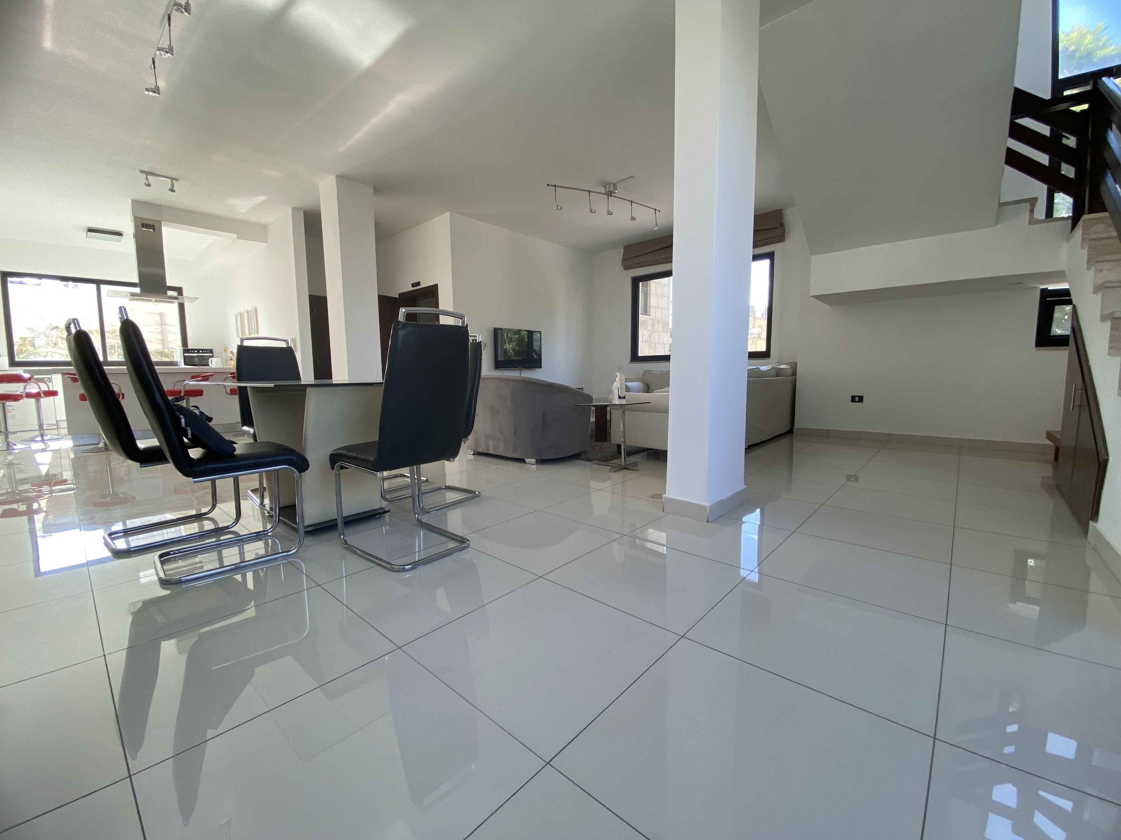 A spacious, modern hotel room with a large, tiled floor, a seating area with two chairs, a sofa, and a small table.