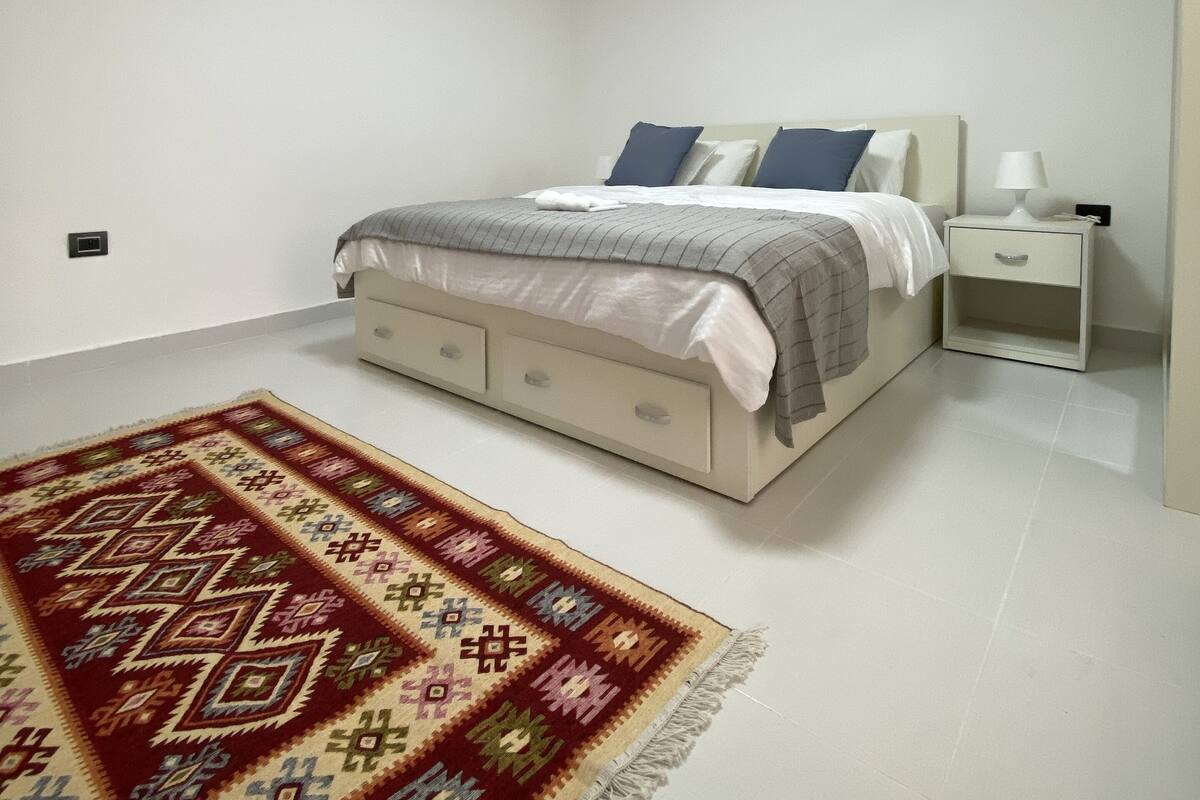 A bedroom with a bed, nightstand, and bedside lamp.