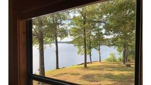 A window view of a lake with trees and grassy area. - Lake house with million dollar view & hot tub (Perryville)