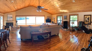 A spacious room with a wooden ceiling, a dining area with a round table and chairs, a sofa, and a telescope. - Lake house with million dollar view & hot tub (Perryville)