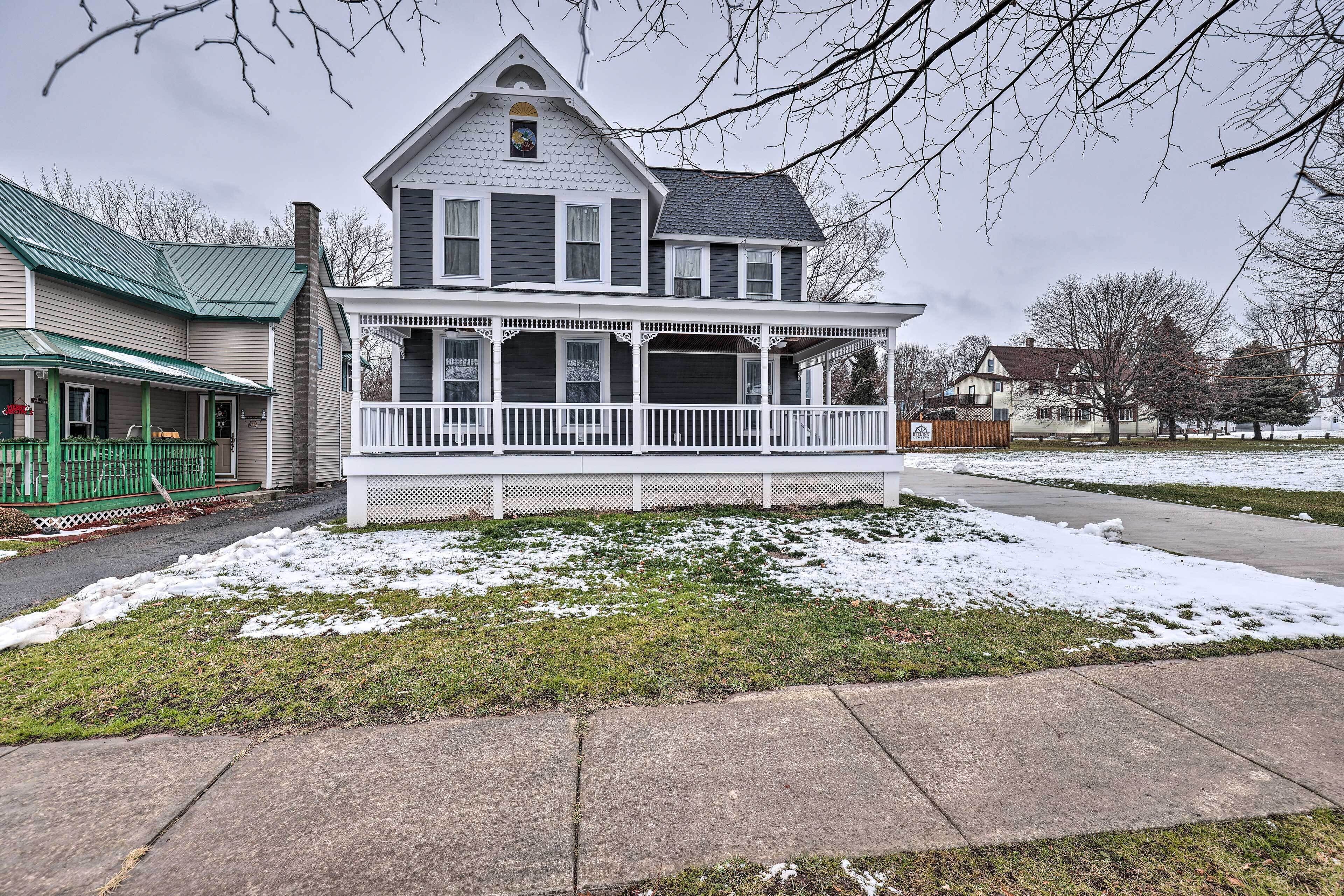 A two-story house with a porch and a green roof.