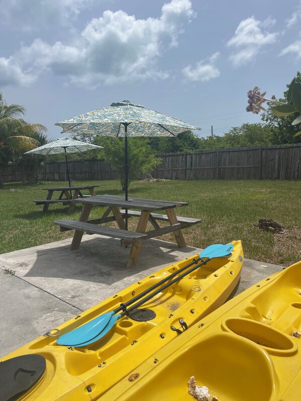 A picnic table with a yellow kayak and an umbrella in a backyard. - Newly renovated home with Kayaks + Pool (Spanish Wells)