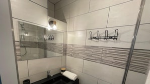 Un baño moderno con un lavabo negro, un espejo, una toalla y una ducha.