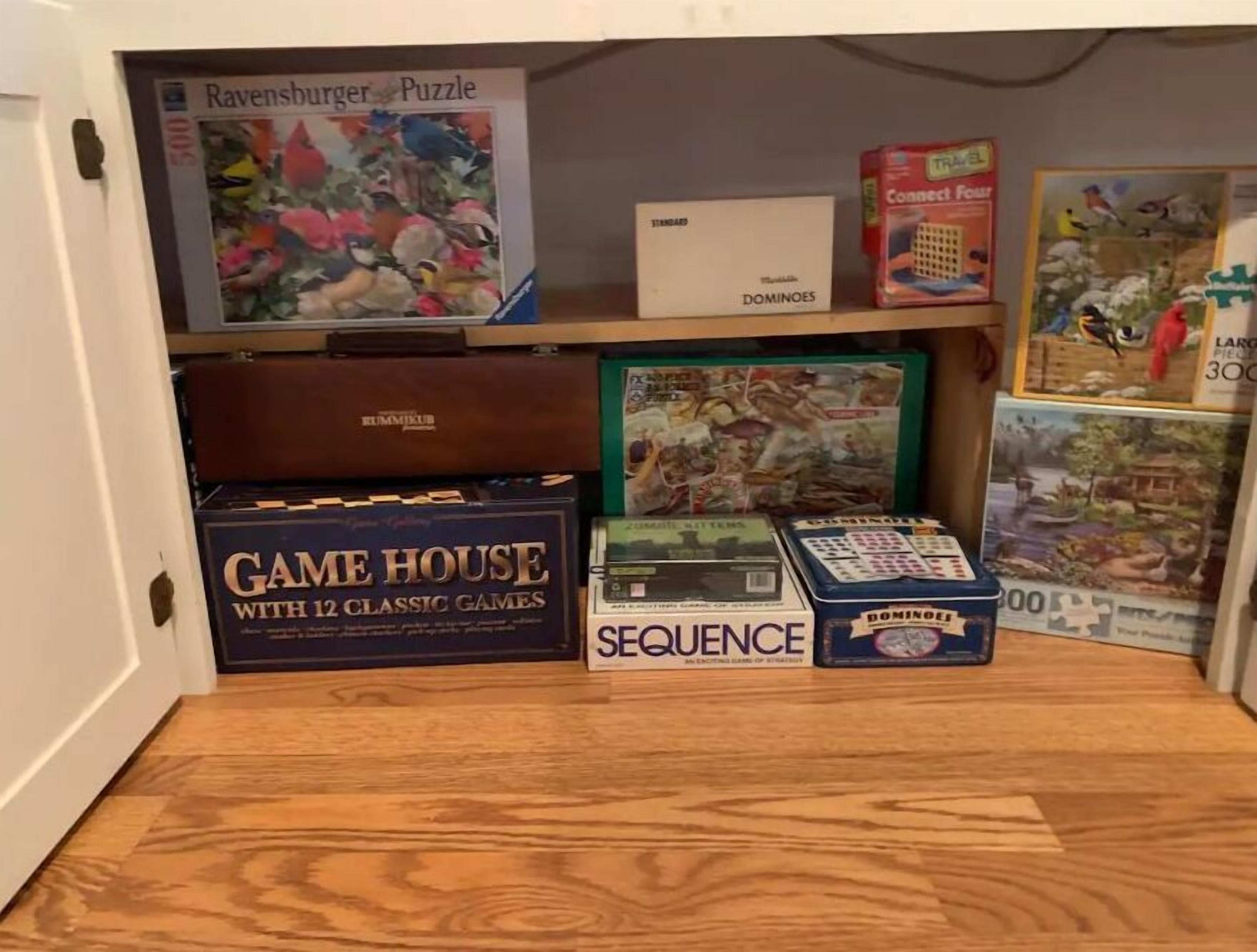 Ein Holztisch mit einer Spielbox mit dem Aufdruck „GAME HOUSE WITH 12 CLASSIC GAMES“ und weiteren Brettspielen.