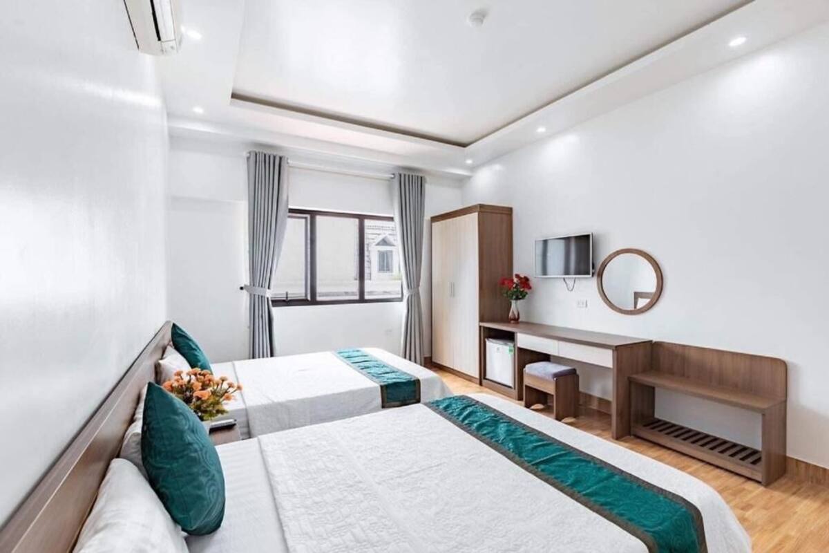 Habitación de hotel con dos camas, un escritorio, un espejo y una ventana con cortinas.