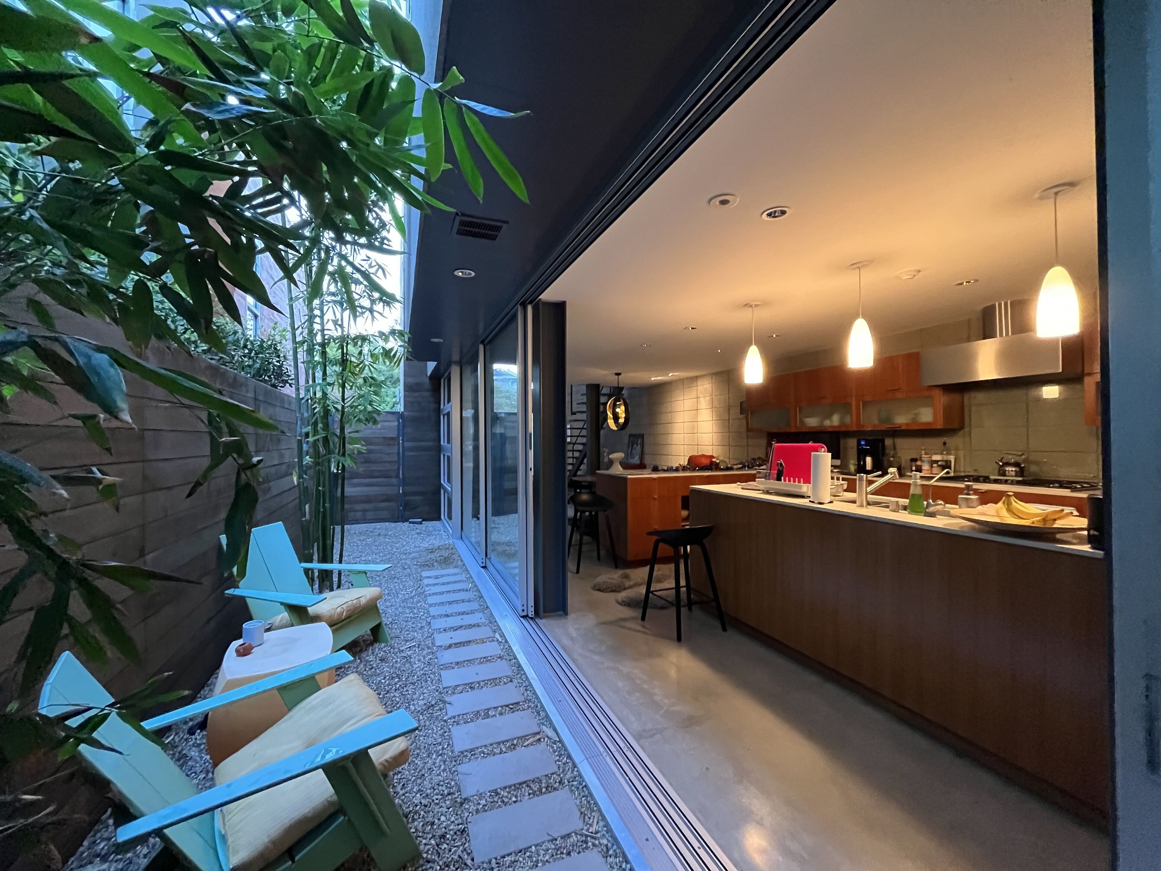 A modern kitchen with a central island, wooden cabinets, and pendant lighting.