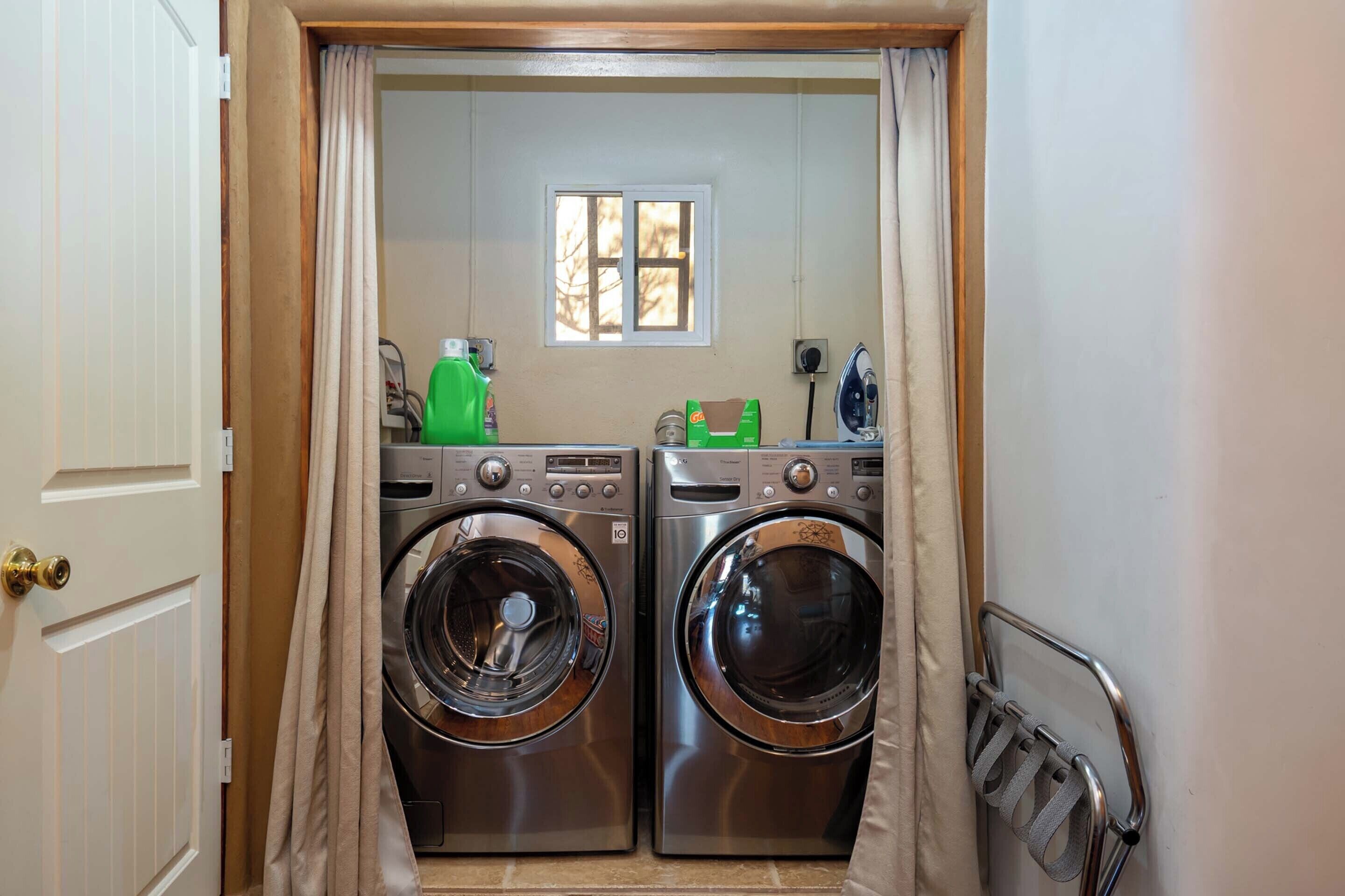 A laundry area with two front-loading washing machines, a window, and a small iron.