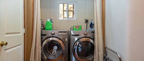 A laundry area with two front-loading washing machines, a window, and a small iron.