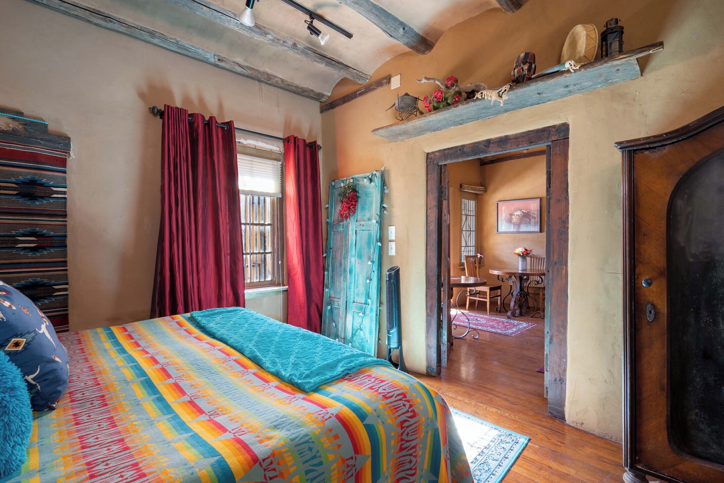 A bedroom with a colorful striped bedspread, a wooden ceiling, and a rustic door.