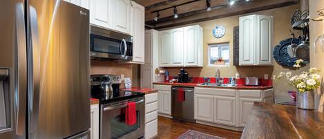A modern kitchen with stainless steel appliances, white cabinetry, and a wooden bench.