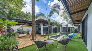 A modern house with a wooden deck, artificial grass, and outdoor furniture. - 350m to Beach - Guitar-shaped Pool Kitchen - BBQ Casa Guitarra (Tempate)