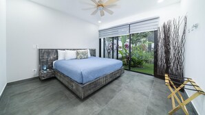 A modern bedroom with a large bed, a ceiling fan, and a view of a garden through a sliding door. - 350m to Beach - Guitar-shaped Pool Kitchen - BBQ Casa Guitarra (Tempate)