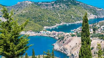 Une ville côtière avec des bâtiments le long du littoral, une baie où sont amarrés des bateaux et, en arrière-plan, un paysage montagneux.