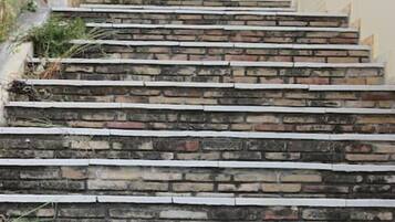 Un escalier en pierre menant à un bâtiment doté d’une porte bleue et d’un balcon.