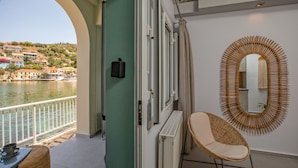Ein Balkon mit Blick auf ein Gewässer und Gebäude, ein Korbstuhl, ein Heizkörper und ein an der Wand befestigter Spiegel.