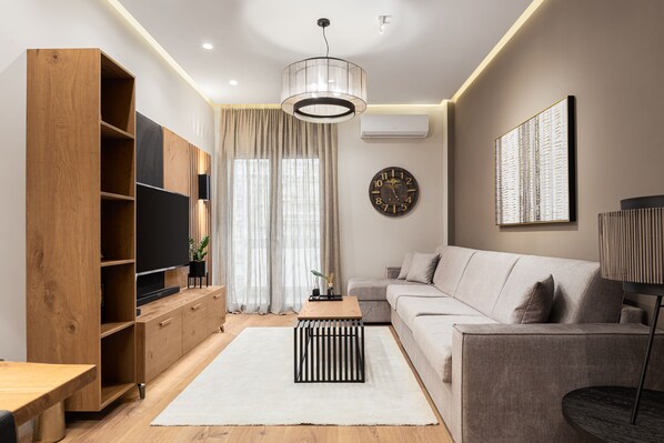 A modern living room with a wooden entertainment unit, a sofa, a coffee table, and a large clock on the wall.