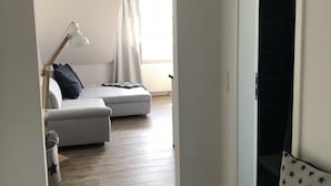 A modern living room with a grey sofa, a small wooden table, and a lamp. - Elbblick 2, NEW, very modern apartments on the Dove Elbe, close to the city center (Hamburg)