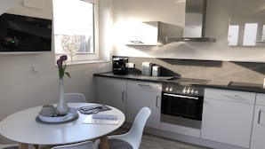 A modern kitchen with white cabinets, a built-in oven, and a coffee maker. - Elbblick 2, NEW, very modern apartments on the Dove Elbe, close to the city center (Hamburg)