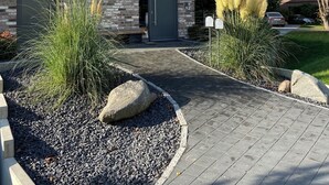 A modern brick house with a stone facade, a dark entrance door, and a paved driveway leading to the front. - Elbblick 2, NEW, very modern apartments on the Dove Elbe, close to the city center (Hamburg)