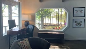 A room with a large octagonal window, a desk with a computer, a chair, and a couch. There are two butterfly wall art pieces. - Lake house, amazing view, hot tub (Perryville)