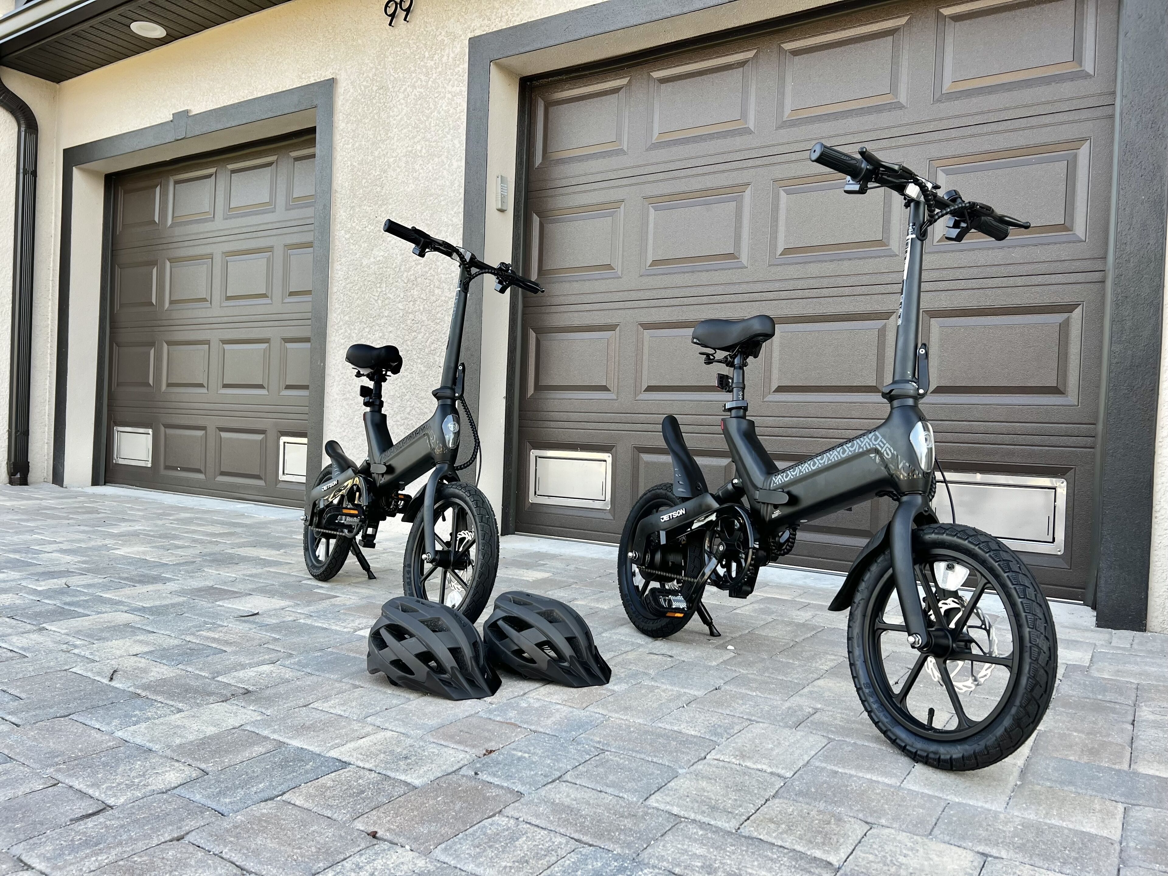 Två elcyklar parkerade framför ett garage med två garageportar.