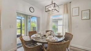 A dining area with a round table set for six, surrounded by wicker chairs.