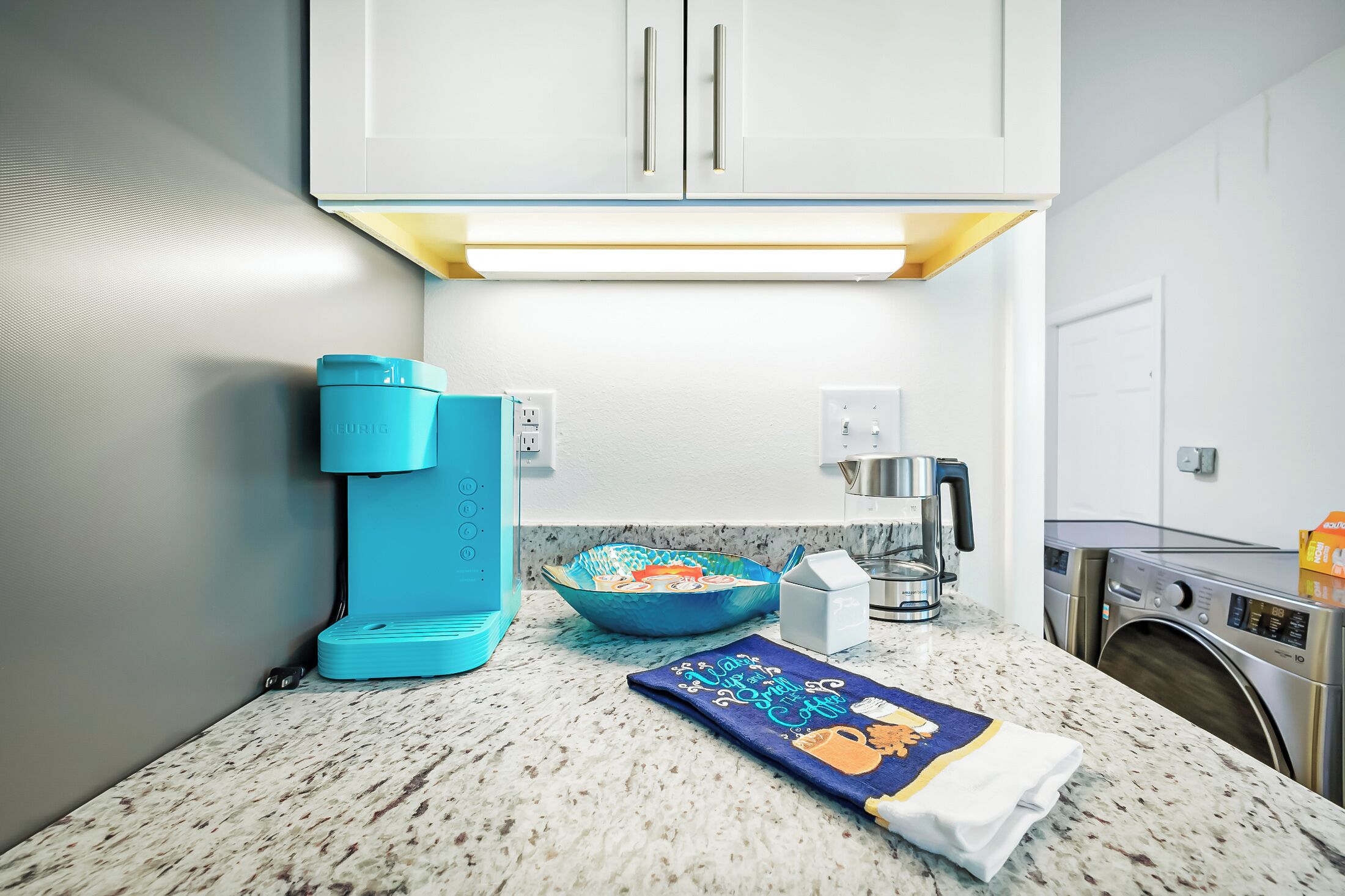 A kitchen with a coffee maker, a bowl, and a towel on the counter.