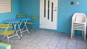 A room with a blue wall, a white door, a tiled floor, and a table with yellow chairs. - Cayo Laurel at Guayacan Guest House (Lajas)