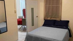 A room with two beds, a ceiling fan, a window with curtains, and a door leading to another room. - Cayo Laurel at Guayacan Guest House (Lajas)